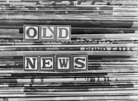 Old newspapers stacked and "Old News" is written in Block Letters. B&W 