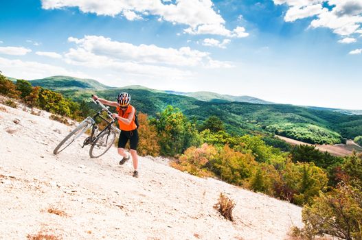 female cyclist raises his mountain bike on the mountain