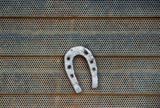 Horsheshoe on rusty metal radiator grill detail.