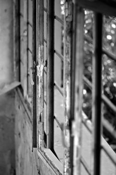 Rusty window frame in abandoned house. Black and white, selective focus.