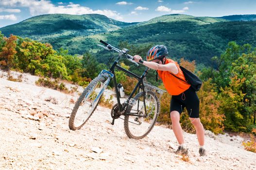 female cyclist raises his mountain bike on the mountain