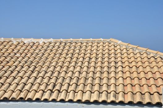 Sloped ceramic tiles roof background. Traditional house against blue sky.