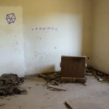 Armchair facing the wall in abandoned house. Drug use paraphernalia on the floor.