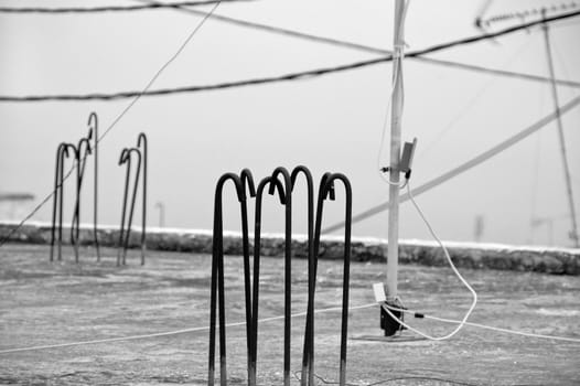 Concrete urban rooftop, construction bars, antenna and wires. Black and white.