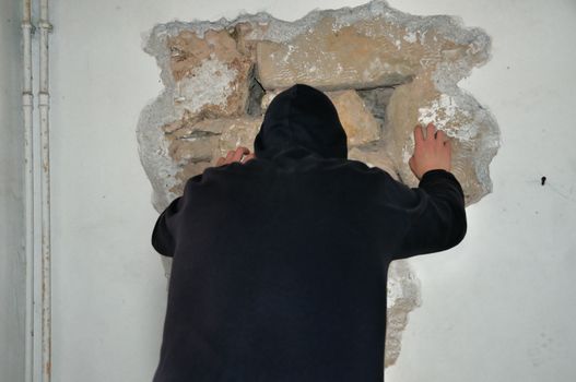 Man breaking down a wall with his bare hands.