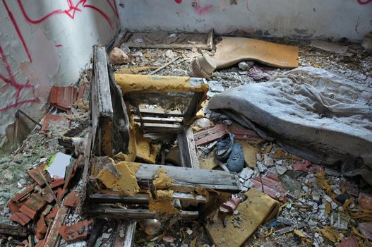 Weathered armchair in abandoned deteriorating house interior.