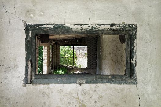 Wooden weathered window frame and crumbling wall in abandoned building.