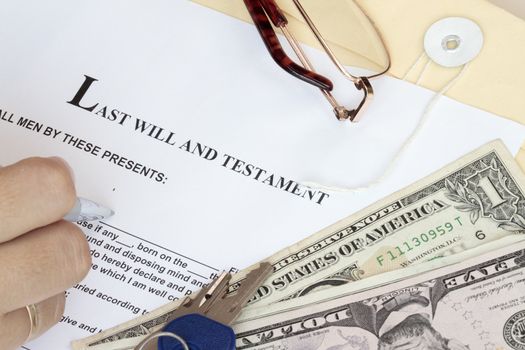 Last Will and Testament with dollars and hand ready for fill-up the form.
