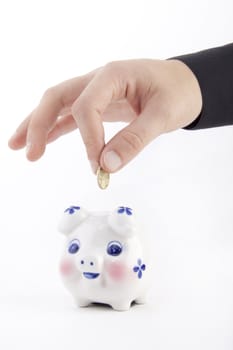 Hand inserting coin into piggy-bank