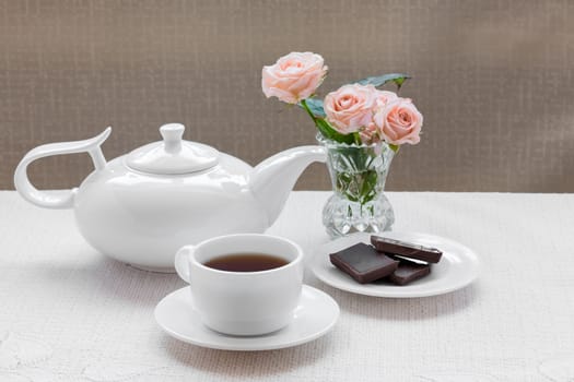 teapot, cup, roses, and chocolate on a plate