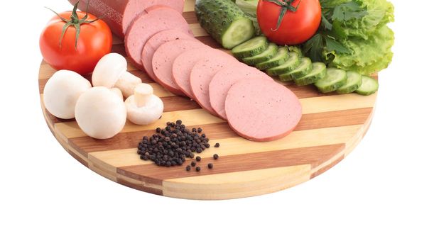 Sliced sausage , butter and vegetables on a wooden plate