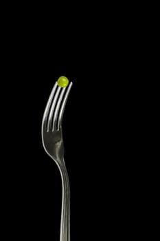 Fresh green peas on a silver fork, over blackbackground.