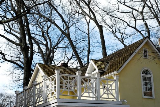 Yellow house with white balcony surrounded by oak trees