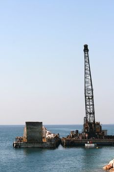 floating crane unloading flat barge full of stones
