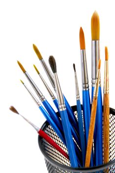 Paintbrushes in a metal mesh holder on white background