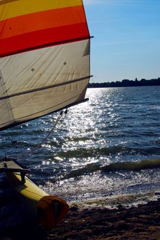 Catamaran on a beach with backlit sail