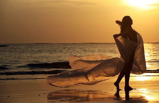 The beautiful woman on a coast on a sunset