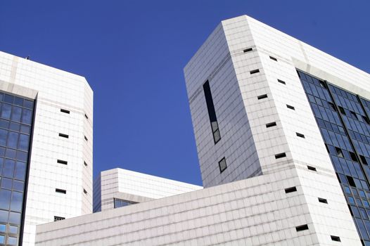 Modern sleek office building with white marble tiles in a blue sky