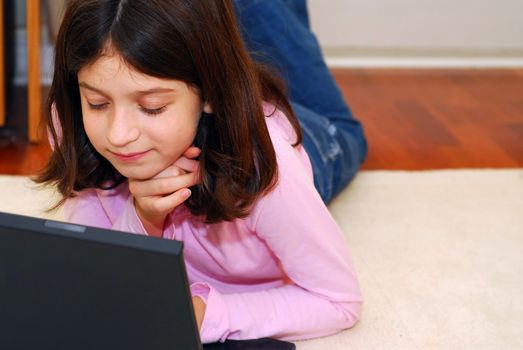 Portrait of a young girl lying on the floor and looking into computer