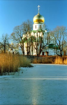 Russian church near iced pond with reflection of golden cupola
