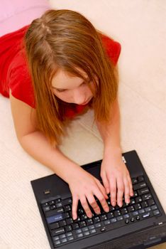 Young girl lying on the floor with portable computer