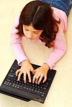 Young girl lying on the floor with portable computer