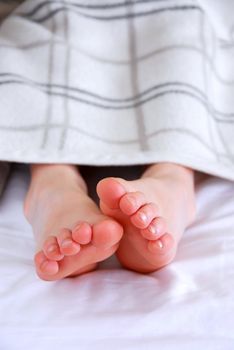 Child's feet sticking out of a blanket in a bed