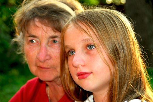 Portrait of grandmother and granddaughter in summer park, focus on the girl