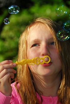 Young girl blowing soap bubbles in a park