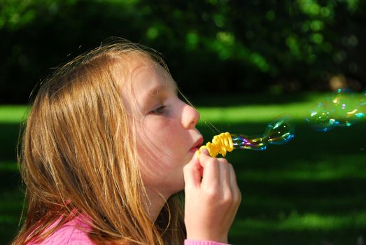 Young girl blowing soap bubbles in a park