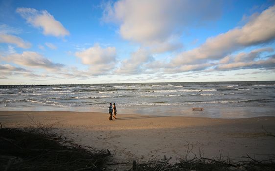 The man and the woman walk on a winter beach. Coast of the Baltic sea