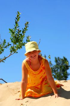 Young girl sitting on top of a sand dune