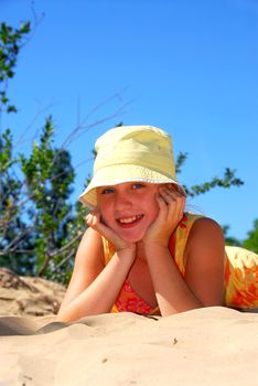 Young girl lying on top of a sand dune