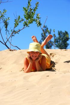 Young girl lying on top of a sand dune