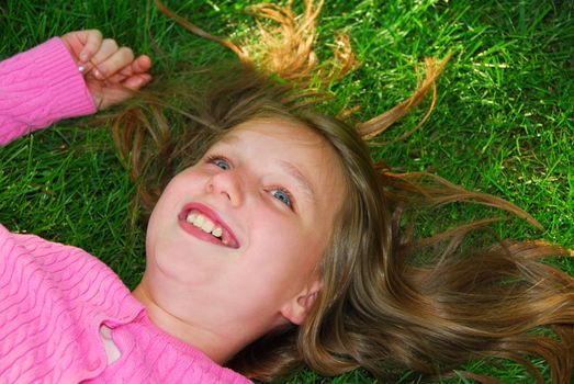 Young girl relaxing on green grass outside