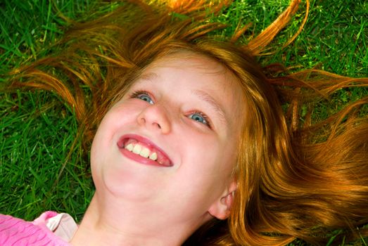 Portrait of a young girl relaxing on green grass outside