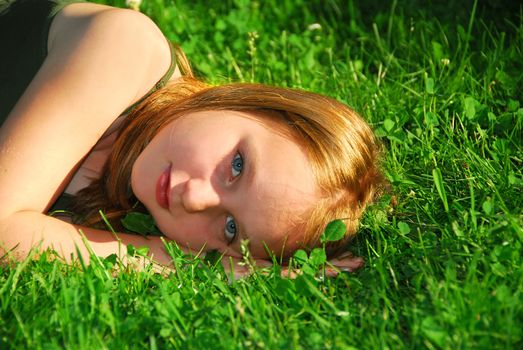 Young pretty girl lying on green grass outside 