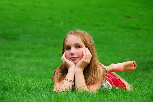 Young girl lying on green grass in the summer