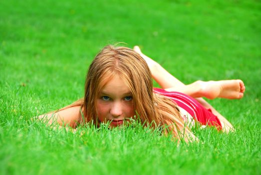 Young girl lying on green grass in the summer
