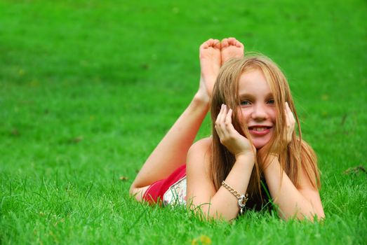 Young girl lying on green grass in the summer