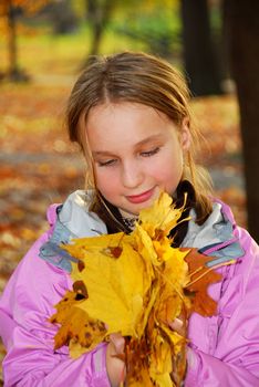 Young girl holding a pile of autumn maple leaves