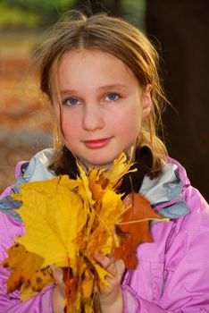 Young girl holding a pile of autumn maple leaves