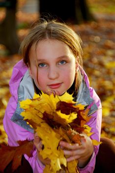 Portrait of a young girl holding autumn leaves