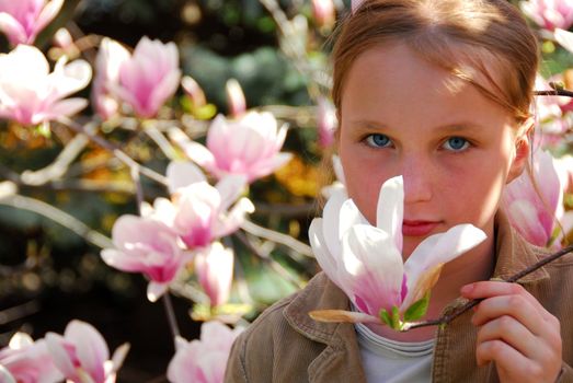 Beautiful young girl with pink magnolia flower