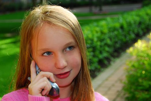 Preteen girl talking on cell phone outside