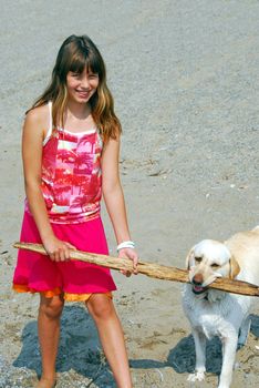 Young pretty girl playing with a dog on a sandy beach