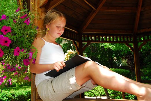 Young girl sitting in a gazeebo reading a book
