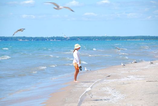 Young girl on a beach among flying seagulls