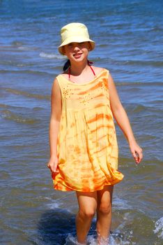 Young girl running in shallow water on a beach