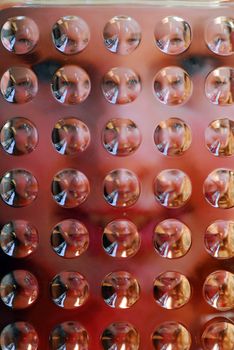 Portrait of a girl photographed through textured glass resulting in many faces on the background of one face; focus on the glass surface